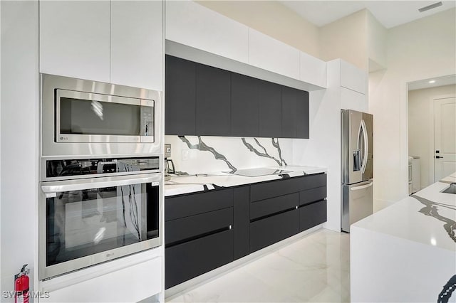 kitchen with decorative backsplash, white cabinets, light stone countertops, and appliances with stainless steel finishes