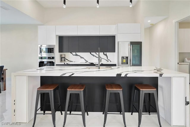 kitchen featuring white cabinetry, a breakfast bar, a large island, and appliances with stainless steel finishes