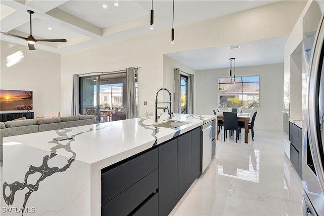 kitchen featuring decorative light fixtures, a wealth of natural light, sink, and a large island with sink