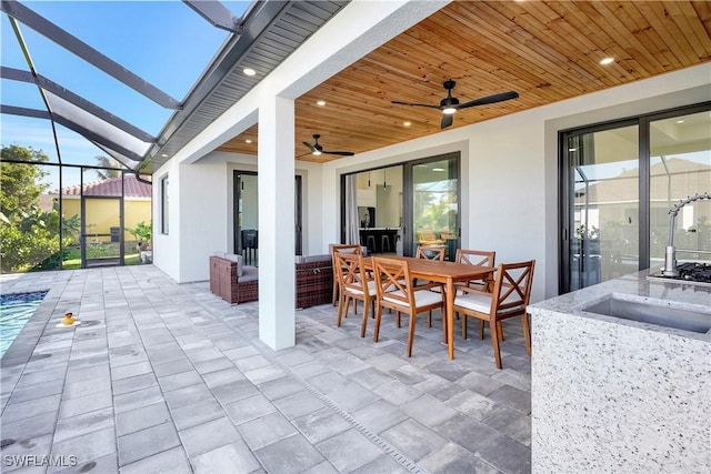 view of patio featuring ceiling fan, a lanai, and sink