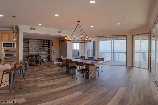 dining area with crown molding, a chandelier, and hardwood / wood-style flooring