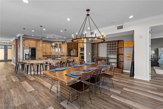 dining area featuring hardwood / wood-style flooring, crown molding, sink, and a notable chandelier