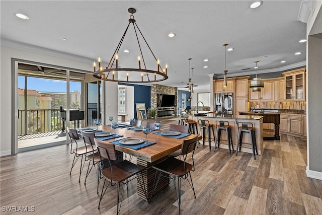 dining area with ornamental molding, a chandelier, a textured ceiling, and light hardwood / wood-style floors