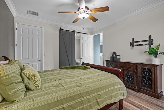 bedroom with hardwood / wood-style floors, ceiling fan, a barn door, and ornamental molding