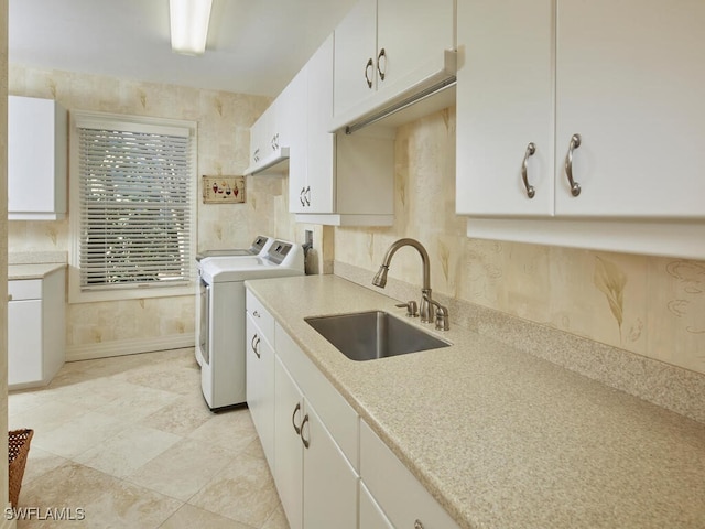 clothes washing area featuring cabinet space, washing machine and dryer, and a sink