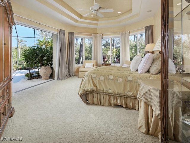 carpeted bedroom with a tray ceiling, access to outside, multiple windows, and recessed lighting