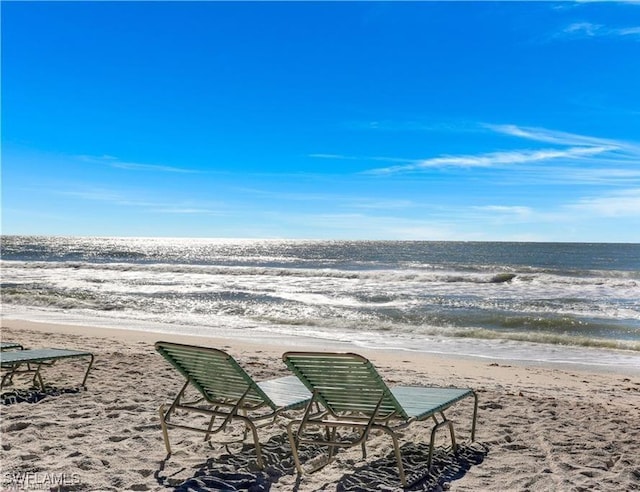 view of property's community with a water view and a beach view