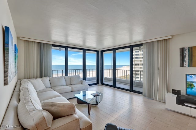 living room featuring a wealth of natural light, a water view, and expansive windows