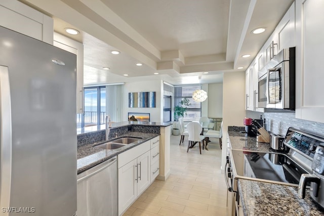 kitchen with appliances with stainless steel finishes, white cabinetry, a wealth of natural light, and sink