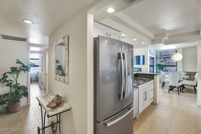 kitchen featuring a kitchen breakfast bar, dark stone countertops, a textured ceiling, appliances with stainless steel finishes, and white cabinetry