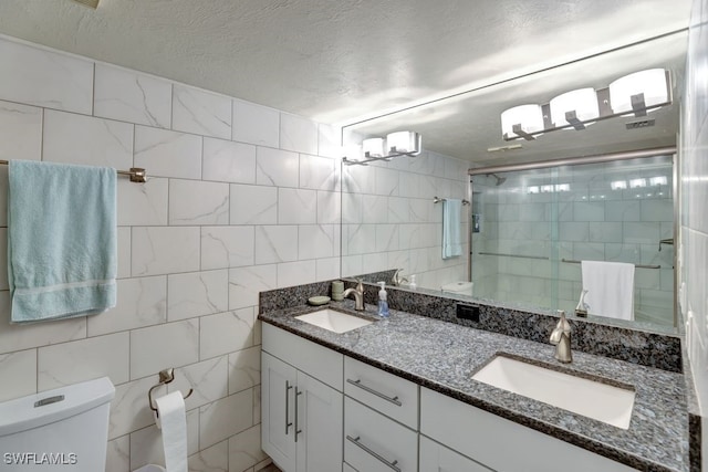 bathroom featuring a textured ceiling, an enclosed shower, toilet, vanity, and tile walls