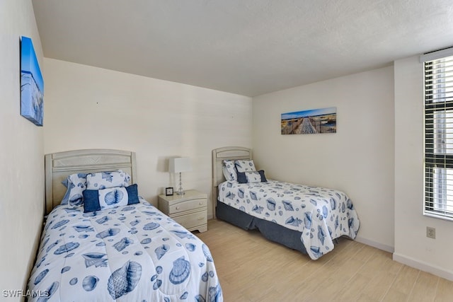 bedroom featuring a textured ceiling and light hardwood / wood-style flooring