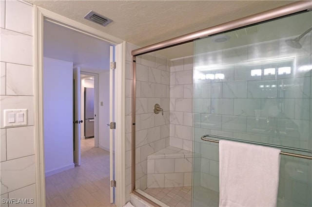 bathroom with a shower with door and a textured ceiling