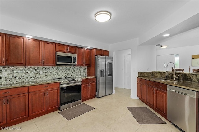 kitchen with sink, dark stone countertops, stainless steel appliances, and tasteful backsplash