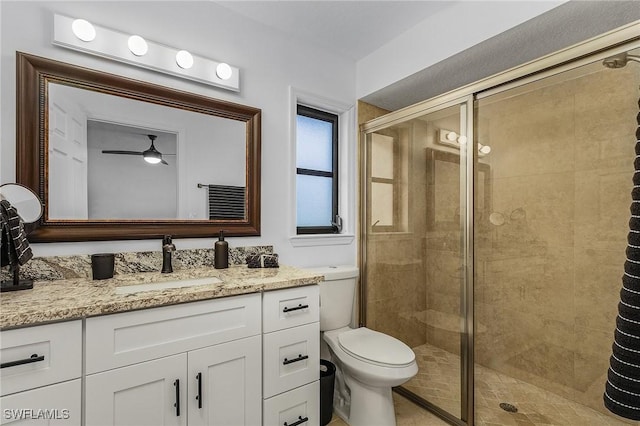 bathroom with vanity, a shower with door, toilet, and ceiling fan