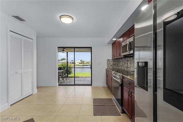 kitchen with decorative backsplash, appliances with stainless steel finishes, light tile patterned floors, and dark stone counters