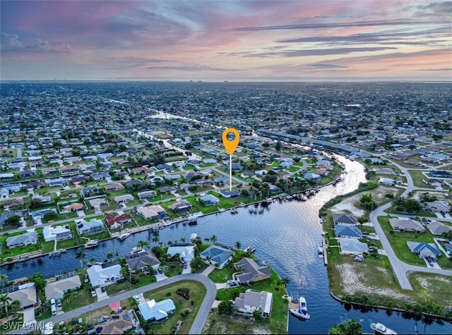 aerial view at dusk featuring a water view