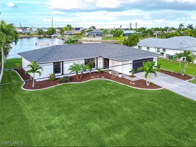 view of front of home with a front yard, a water view, and a garage