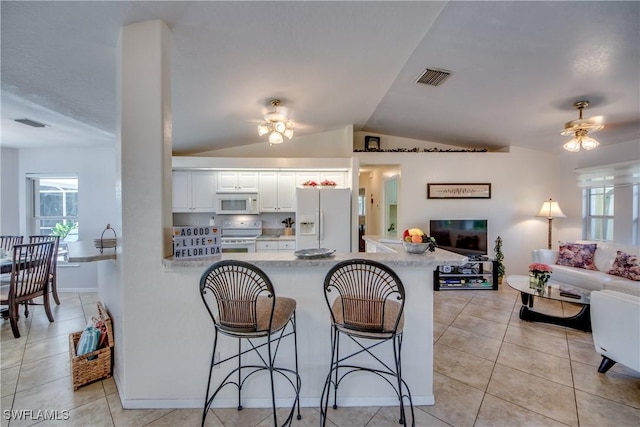 kitchen featuring white appliances, white cabinets, vaulted ceiling, a kitchen bar, and kitchen peninsula