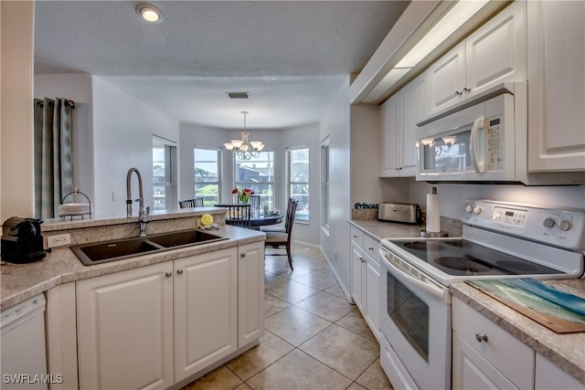 kitchen with a textured ceiling, white appliances, sink, an inviting chandelier, and white cabinetry