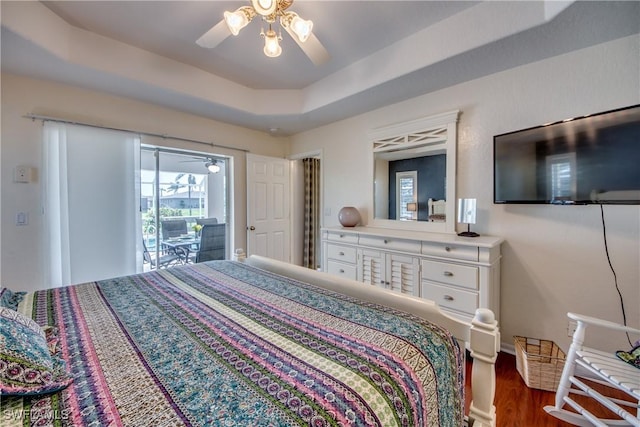 bedroom featuring ceiling fan, a raised ceiling, dark wood-type flooring, and access to outside