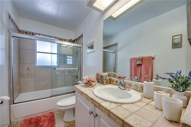 full bathroom featuring a skylight, tile patterned floors, bath / shower combo with glass door, vanity, and toilet