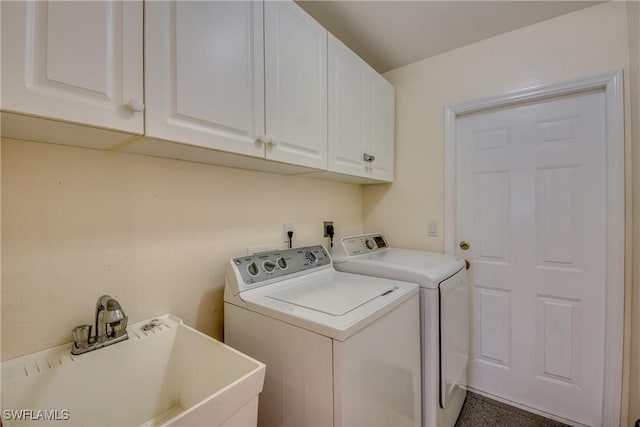 laundry room featuring washing machine and clothes dryer, cabinets, and sink