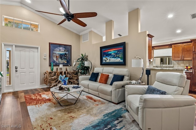 living room with wood-type flooring, lofted ceiling, ceiling fan, and ornamental molding