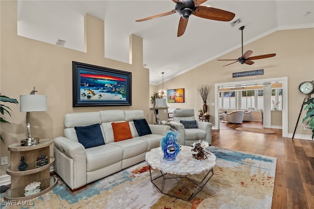 living room with ceiling fan with notable chandelier, hardwood / wood-style flooring, high vaulted ceiling, and crown molding