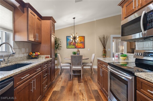 kitchen featuring pendant lighting, sink, dark hardwood / wood-style floors, appliances with stainless steel finishes, and light stone counters