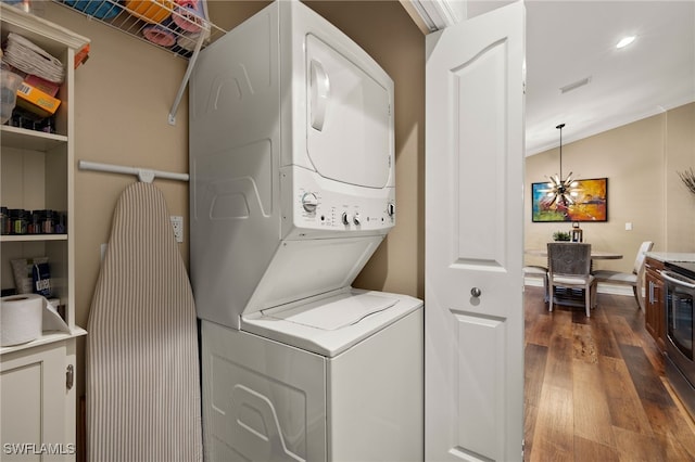 laundry room featuring hardwood / wood-style floors, stacked washing maching and dryer, and crown molding