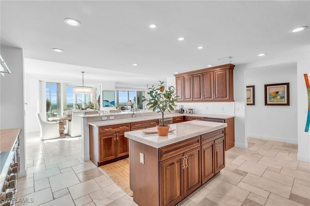 kitchen featuring kitchen peninsula, decorative backsplash, a center island with sink, and pendant lighting