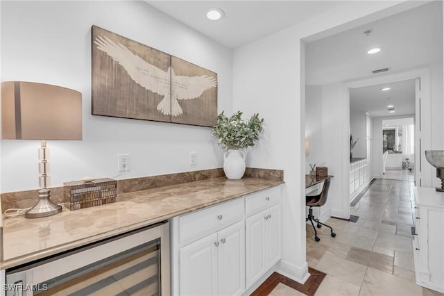 bar featuring white cabinets, light stone countertops, and beverage cooler