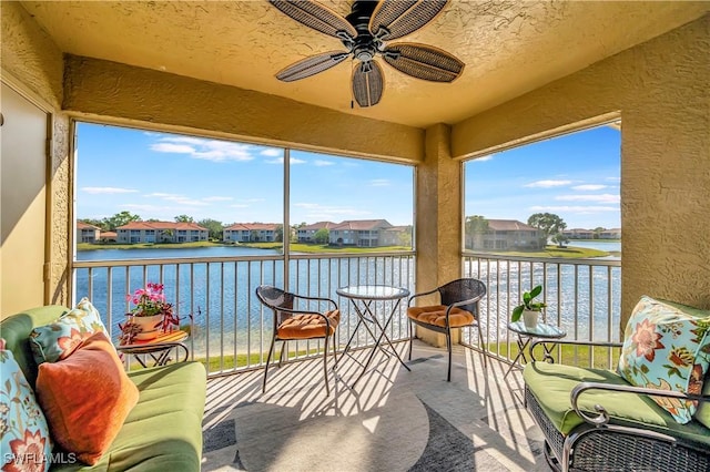 sunroom / solarium with a water view, ceiling fan, and a healthy amount of sunlight