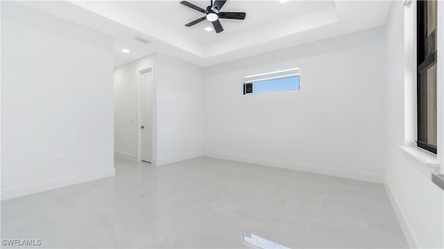 empty room featuring a raised ceiling and ceiling fan