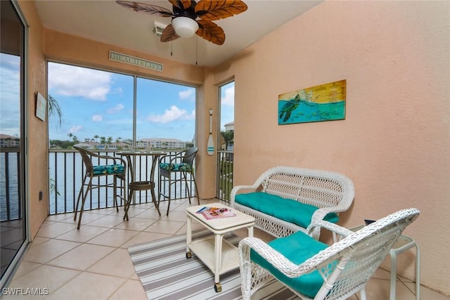 sunroom / solarium featuring ceiling fan and a water view