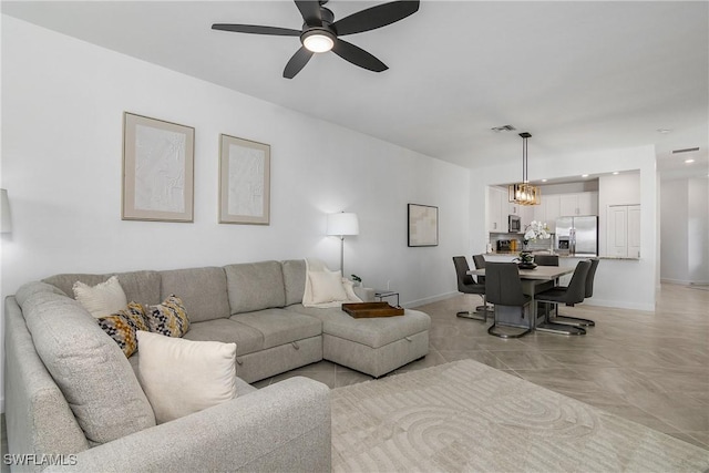 tiled living room featuring ceiling fan with notable chandelier