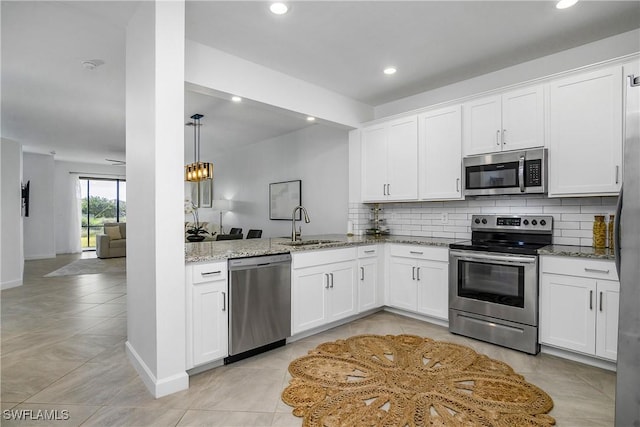 kitchen featuring light stone countertops, white cabinetry, stainless steel appliances, sink, and kitchen peninsula