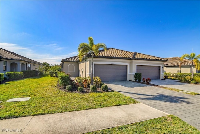 mediterranean / spanish house featuring a garage, stucco siding, a tile roof, decorative driveway, and a front yard