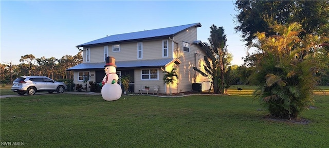 view of front of house with central AC and a front lawn