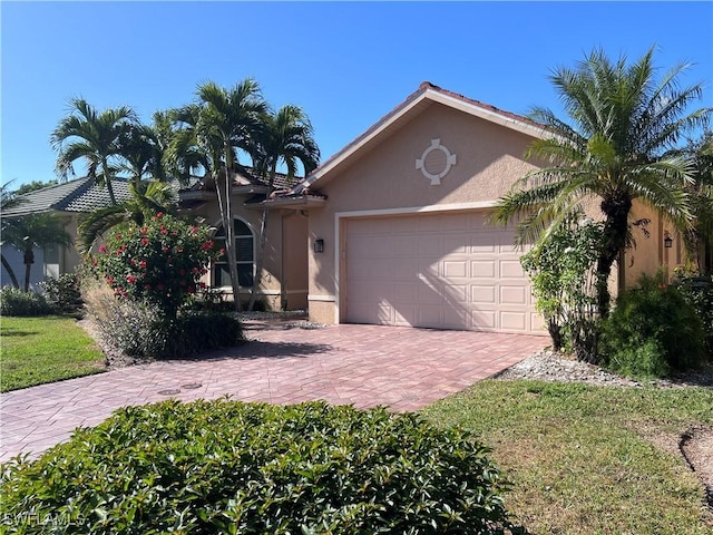 view of front of property with stucco siding, decorative driveway, and a garage