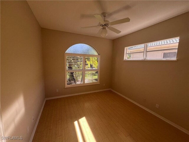 empty room with hardwood / wood-style flooring, ceiling fan, and a healthy amount of sunlight