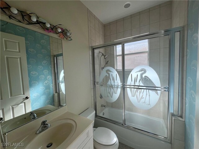 full bathroom featuring toilet, vanity, and combined bath / shower with glass door