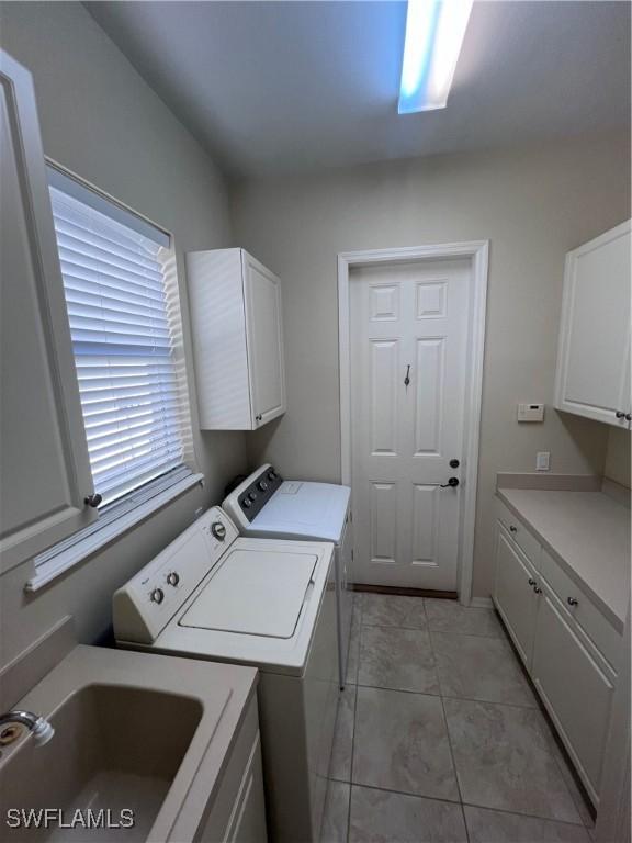 clothes washing area featuring cabinets, separate washer and dryer, sink, and light tile patterned floors