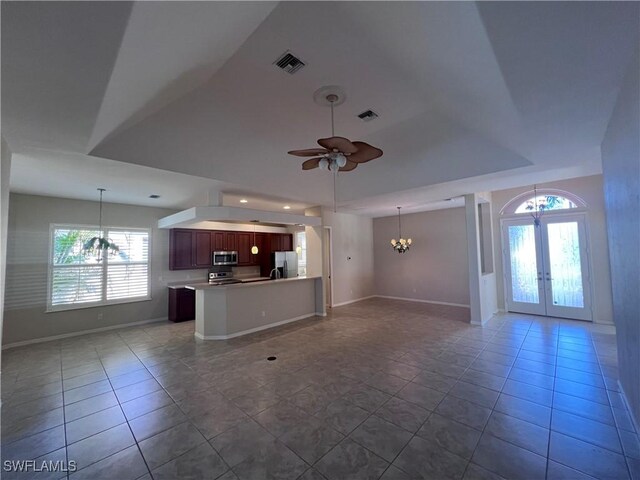 unfurnished living room with tile patterned floors, french doors, and ceiling fan with notable chandelier