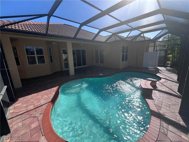 view of pool featuring a patio, glass enclosure, and ceiling fan