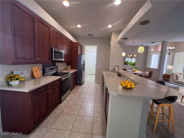 kitchen with stainless steel appliances, a breakfast bar area, a notable chandelier, and sink