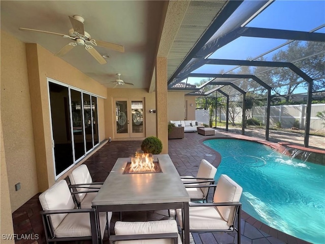 view of pool with a lanai, pool water feature, ceiling fan, a patio area, and an outdoor living space with a fire pit