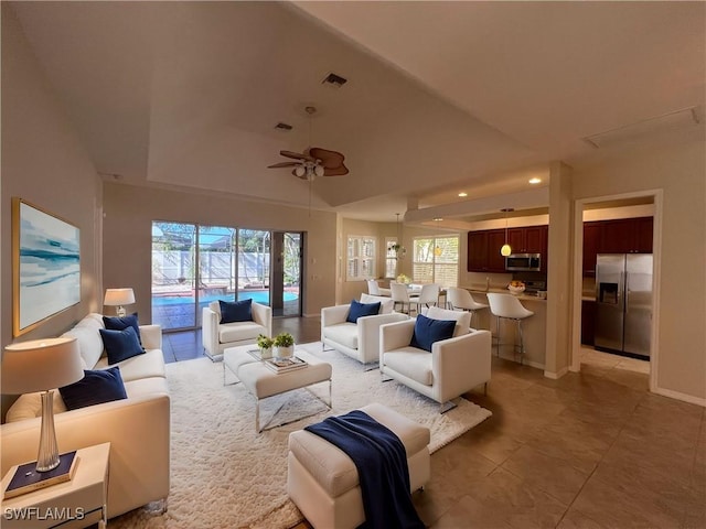 living room featuring a raised ceiling, recessed lighting, a healthy amount of sunlight, and ceiling fan