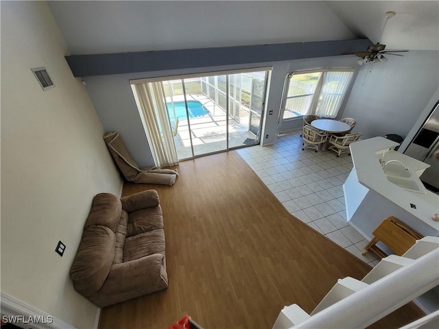 living room with ceiling fan, light tile patterned floors, and vaulted ceiling